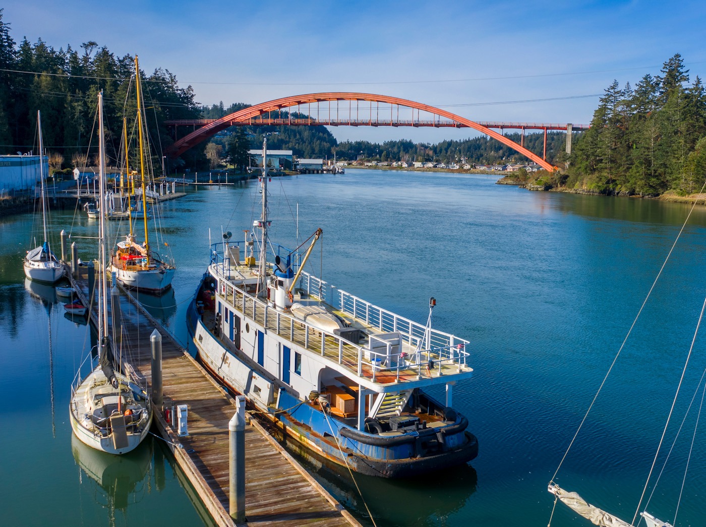 Boats docked along the Swinomish Channel in La Conner with the red Rainbow Bridge in the background